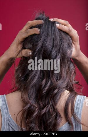 femme blanche avec de longs cheveux attachés en arrière, sa tête tenue doucement par les mains d'un homme noir. Cette scène représente l'inclusivité, la fluidité du genre, non binari Banque D'Images