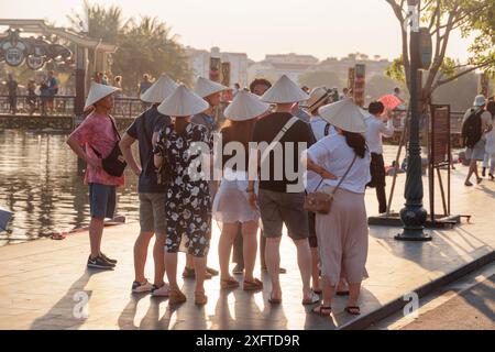 Hoi an (Hoian), Vietnam - 11 avril 2018 : touristes dans les chapeaux traditionnels vietnamiens en bambou achetés dans une boutique de souvenirs. Banque D'Images