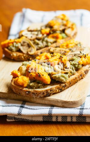 Planche à découper avec toasts à l'avocat aux champignons et cheddar végétalien (carottes, levure nutritionnelle, moutarde) Banque D'Images