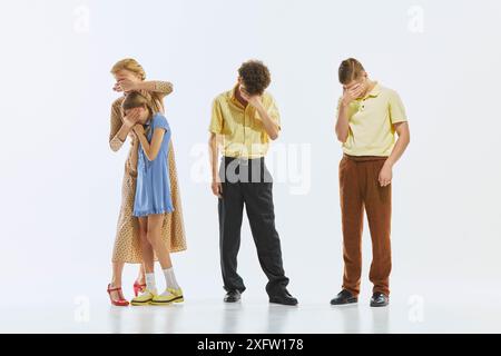 Quatre personnes, une femme, une jeune fille et deux hommes debout dans la rangée, tous couvrant les visages avec les mains, peut-être dans la détresse et l'embarras. Honte, regret Banque D'Images