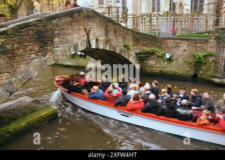 30-10-2014 Bruges, Belgique - Un bateau rempli de touristes glisse sous un pont pittoresque dans les canaux de Bruges Banque D'Images