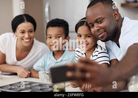 Famille heureuse, cuisson et selfie avec des ingrédients dans la cuisine pour le matin, se lier ou aimer ensemble à la maison. Mère, père et jeunes enfants avec Banque D'Images