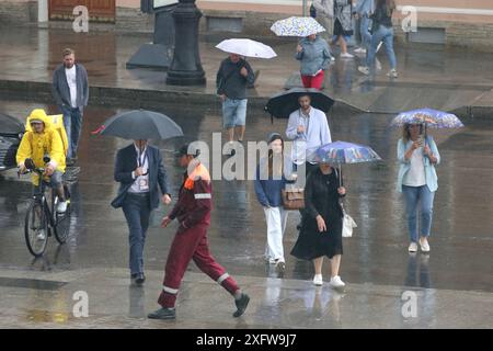 Saint-Pétersbourg, Russie. 04 juillet 2024. Les gens s'abritent sous des parapluies tout en marchant le long de la route sous de fortes pluies dans le centre de Saint-Pétersbourg. (Photo de Maksim Konstantinov/SOPA images/SIPA USA) crédit : SIPA USA/Alamy Live News Banque D'Images