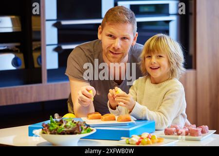 Famille dans la cuisine. Père et fils. L'alimentation saine. Une croissance saine. La prise de poisson citron. Banque D'Images