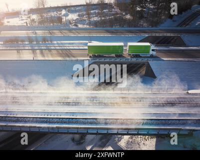 Drone vue d'un camion sur le pont supérieur près des voies ferrées au milieu de la neige Banque D'Images