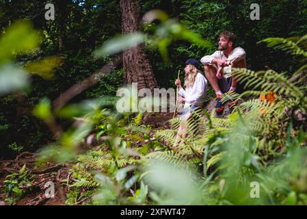 Père et fille se relaxant tout en faisant de la randonnée en forêt Banque D'Images