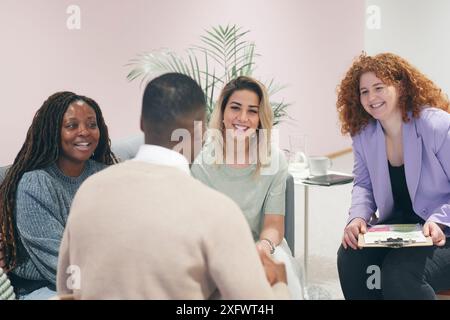 Des femmes d'affaires joyeuses discutant de plans avec un collègue au bureau Banque D'Images