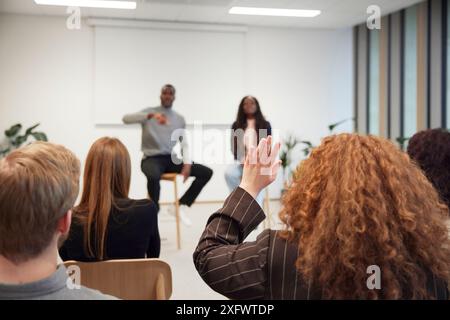 Femme d'affaires levant la main pendant la discussion au bureau Banque D'Images