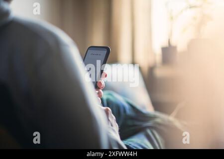 Homme prenant l'aide de l'IA par téléphone intelligent à la maison Banque D'Images