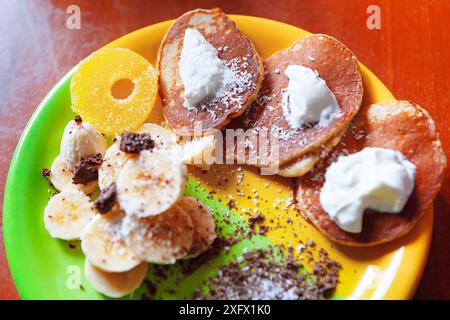 Assiette de crêpes avec bananes et flocons de noix de coco sur le dessus. Assiette appétissante avec un mélange d'options saines Banque D'Images