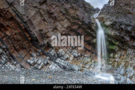 Une petite cascade à Sandy Mouth Beach, près de Bude, Cornwall, Royaume-Uni, mars. Les roches sont en forte baisse de l'âge Carbonifère, du grès et du schiste (mesures Culm). Banque D'Images