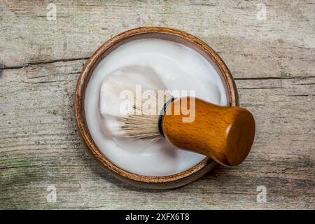 Macro photo horizontale de brosse à raser sanglier dans un bol en bois, reposant sur une surface en bois rustique. Accessoires de rasage traditionnels à l'eau. Banque D'Images