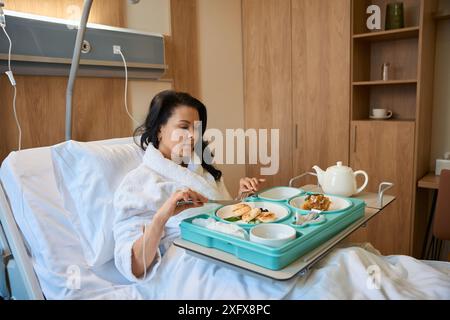 Femme avec IV prend le petit déjeuner au lit Banque D'Images