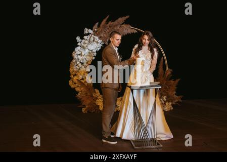 les jeunes mariés se réjoument de couper, de rire et de goûter le gâteau de mariage Banque D'Images