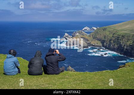 Ornithologues observant le littoral avec des falaises et des piles marines, qui abrite des oiseaux de mer reproducteurs à Hermaness, Unst, îles Shetland, Écosse, Royaume-Uni, mai Banque D'Images