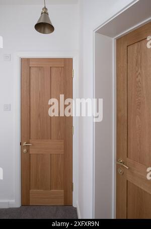 Portes intérieures lambrissées en bois, meubles en laiton et murs peints en blanc. Partie d'une rénovation de maison. Banque D'Images