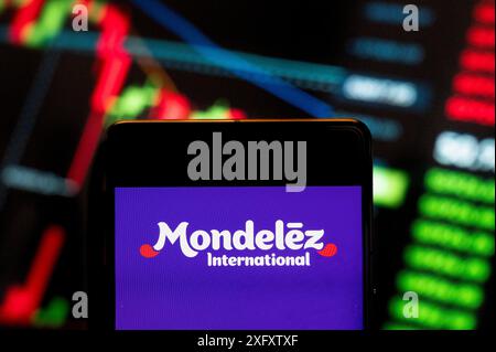 Dans cette illustration photo, la multinationale américaine de confiserie, de nourriture, de holding et de boissons et de snacks, Mondelez International (NASDAQ : MDLZ), logo vu sur un smartphone avec un graphique de l'indice boursier économique en arrière-plan. Banque D'Images