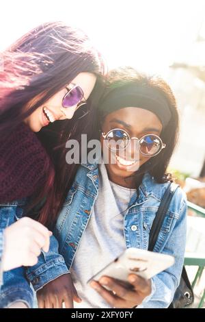 Avoir du plaisir avec vos amis multiraciale smartphone dans une journée de printemps. Banque D'Images