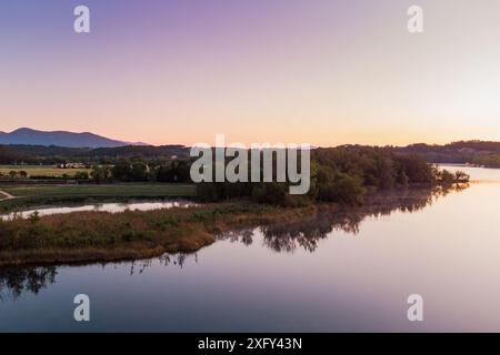 Vue aérienne du lac Banyoles au lever du soleil à Gérone, Catalogne, Espagne. Drone shot de paysage de lac paisible le matin avec une lumière chaude au crépuscule Banque D'Images