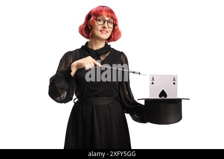 Magicien féminin avec un chapeau haut de gamme et des cartes tenant une baguette isolée sur fond blanc Banque D'Images