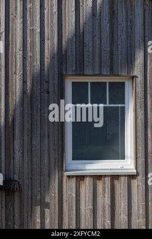 Façade en bois brun avec fenêtre blanche et lumière du soleil latérale Banque D'Images