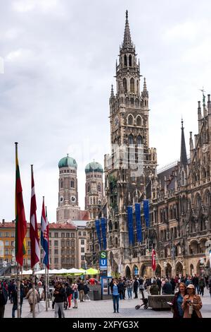 À Munich, l'hôtel de ville avec le carillon se trouve sur Marienplatz, avec les tours jumelles de la Frauenkirche en arrière-plan Banque D'Images