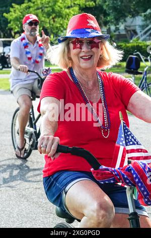 Sullivans Island (États-Unis d'Amérique). 04 juillet 2024. Une femme portant des couleurs patriotiques fait du vélo lors du défilé annuel de vélo et de voiturette de golf célébrant le jour de l'indépendance le 4 juillet 2024 à Sullivans Island, Caroline du Sud. Crédit : Richard Ellis/Richard Ellis/Alamy Live News Banque D'Images