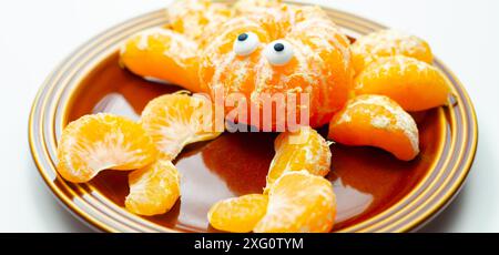 Une assiette de tranches d'orange avec un motif de crabe fait à partir des tranches. Le crabe a deux yeux et est assis sur une plaque brune Banque D'Images
