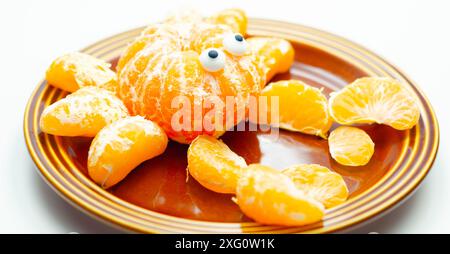 Une assiette de tranches d'orange avec un motif de crabe fait à partir des tranches. Le crabe a deux yeux et est assis sur une plaque brune Banque D'Images