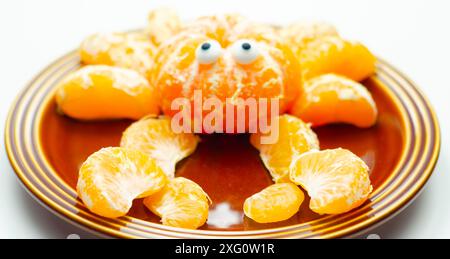 Une assiette de tranches d'orange avec un motif de crabe fait à partir des tranches. Le crabe a deux yeux et est assis sur une plaque brune Banque D'Images