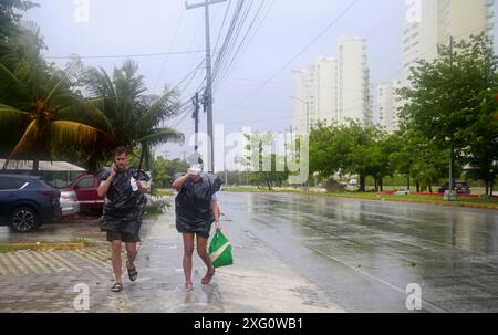 Cancun, Mexique. 5 juillet 2024. Les gens marchent sous la pluie après la chute de l'ouragan Beryl, à Cancun, dans l'état de Quintana Roo, au Mexique, le 5 juillet, 2024. dans les Caraïbes, plus d'un million de personnes ont été touchées par l'ouragan Beryl, ont déclaré vendredi les humanitaires des Nations Unies. Ouragan de catégorie 4 qui a fait au moins 11 morts à ce jour, Beryl a laissé lundi une traînée de destruction à Grenade et Saint-Vincent-et-les Grenadines, puis a touché la Jamaïque mercredi. L'ouragan affecte actuellement le Belize et le Mexique. Crédit : Alberto Valdez/Xinhua/Alamy Live News Banque D'Images