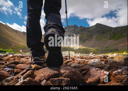 Gros plan de chaussures de randonnée pour femmes marchant le long d'un chemin de pierre dans les montagnes vers le lac Banque D'Images