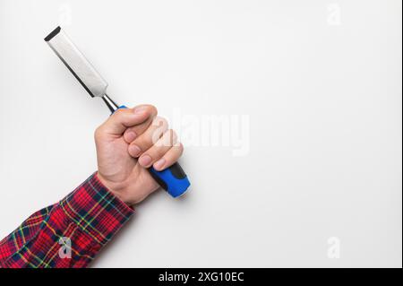 Gros plan de la main d'un homme dans une chemise à carreaux sur un fond blanc avec un ciseau, plan studio Banque D'Images