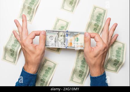 Les mains des hommes tiennent un tas d'argent plié, des billets d'un dollar, remboursent une dette. studio shot, fond blanc Banque D'Images