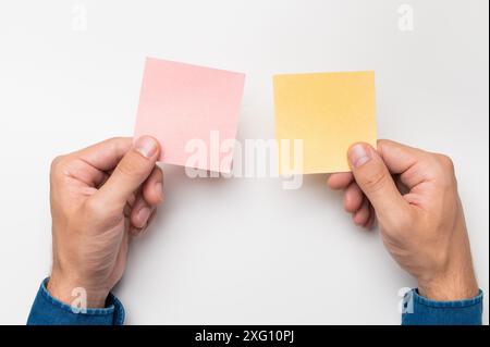 Les mains d'un employé de bureau tiennent des autocollants de couleur pour les notes sur un fond blanc, gros plan Banque D'Images