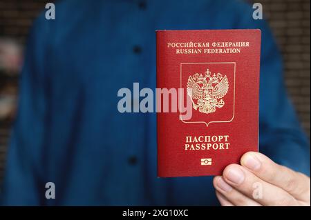 Les mains des hommes tiennent un passeport russe étranger rouge sur le fond d'eux-mêmes dans une chemise, leurs visages ne sont pas visibles. gros plan Banque D'Images