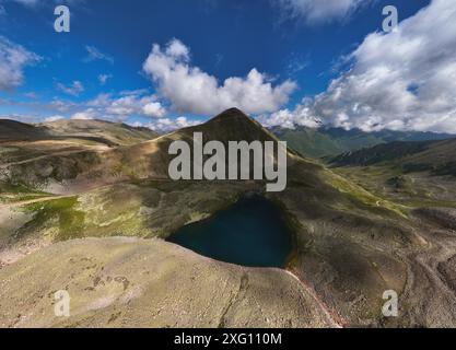 Vue aérienne du lac glaciaire de haute montagne et des sommets de montagne enneigés. Paysage d'un lac alpin par une journée ensoleillée Banque D'Images