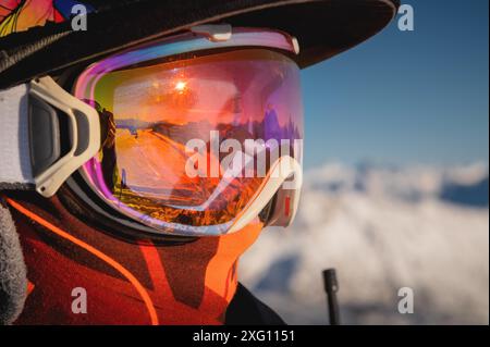 Lunettes de ski avec reflet de montagnes enneigées. Un homme sur une piste de ski se tient de profil et regarde au loin, portrait Banque D'Images