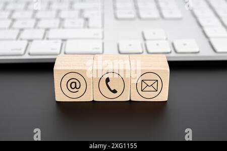 Contactez-nous icônes sur des blocs de bois et clavier d'ordinateur sur le bureau noir. Mise au point sélective Banque D'Images