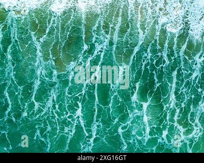 Vue aérienne turquoise tempête vagues océaniques avec de la mousse blanche dans l'océan, eau de mer avec des éclaboussures et de la mousse, fond de vagues vue de dessus, arrière-plan naturel Banque D'Images