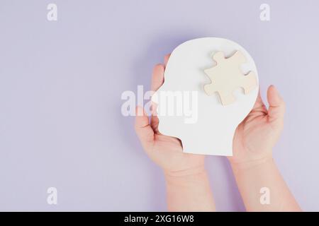 Tenir la tête avec une pièce de puzzle, maladie mentale comme l'autisme, la maladie d'Alzheimer, la conscience d'accident vasculaire cérébral, brainstorming pour des idées, problèmes de mémoire Banque D'Images