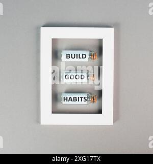 Les mots construire de bonnes habitudes sont debout sur des bouteilles de verre dans un cadre, changer de style de vie, en bonne santé et positive attidude, concept de motivation Banque D'Images