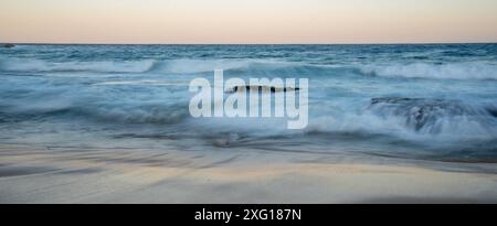 Coucher de soleil au ralenti des vagues d'eau floues qui s'écrasent Banque D'Images