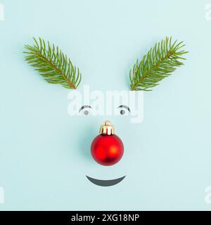 Visage d'un renne avec un nez de boule rouge, des bois de sapin et des yeux amicaux, carte de vœux de joyeux noël Banque D'Images
