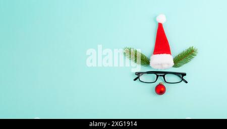 Visage d'un renne avec un nez de boule rouge, des bois de sapin, un chapeau et des lunettes du père noël, carte de vœux de joyeux noël Banque D'Images