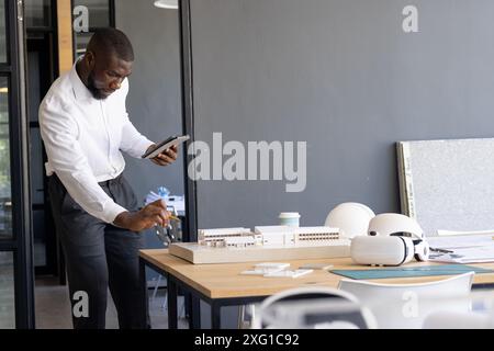 Architecte examinant le modèle réduit et utilisant la tablette dans le bureau moderne, copier l'espace Banque D'Images