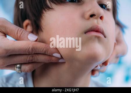 Endocrinologue pédiatrique examinant les ganglions d'un jeune garçon. Banque D'Images