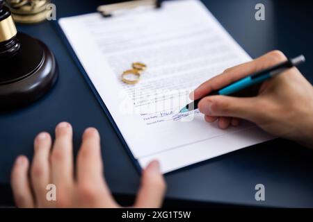 Jeune couple, un caucasien et un hispanique, consultant un avocat au tribunal pour signer un document d'accord de divorce. Banque D'Images