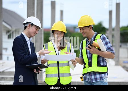 Équipe d'ingénieurs discutant du plan tout en se tenant debout sur le chantier de construction Banque D'Images