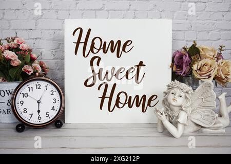 Home Sweet Home message texte avec réveil et décoration de poupée en céramique ange sur fond en bois Banque D'Images